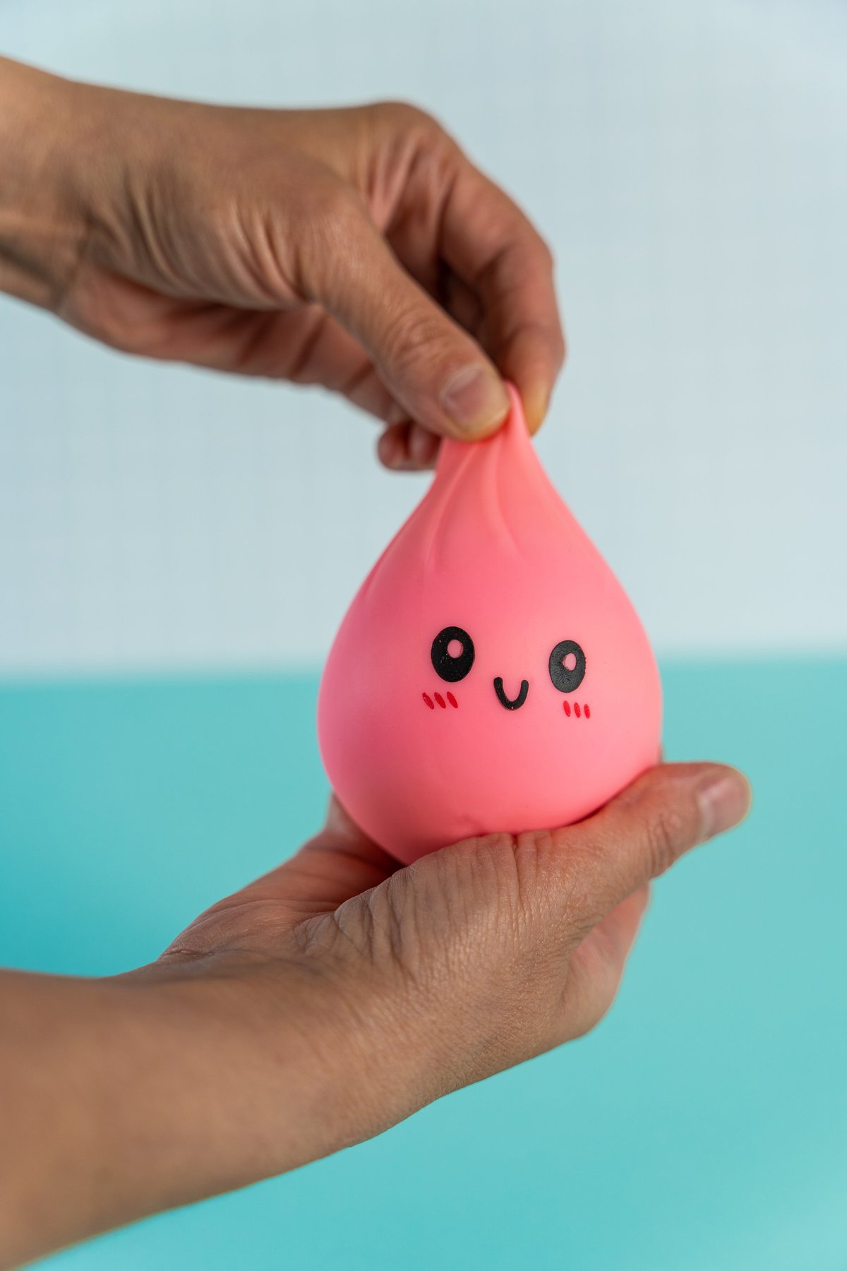 Close-up of a pink squishy toy with a smiling face being squeezed