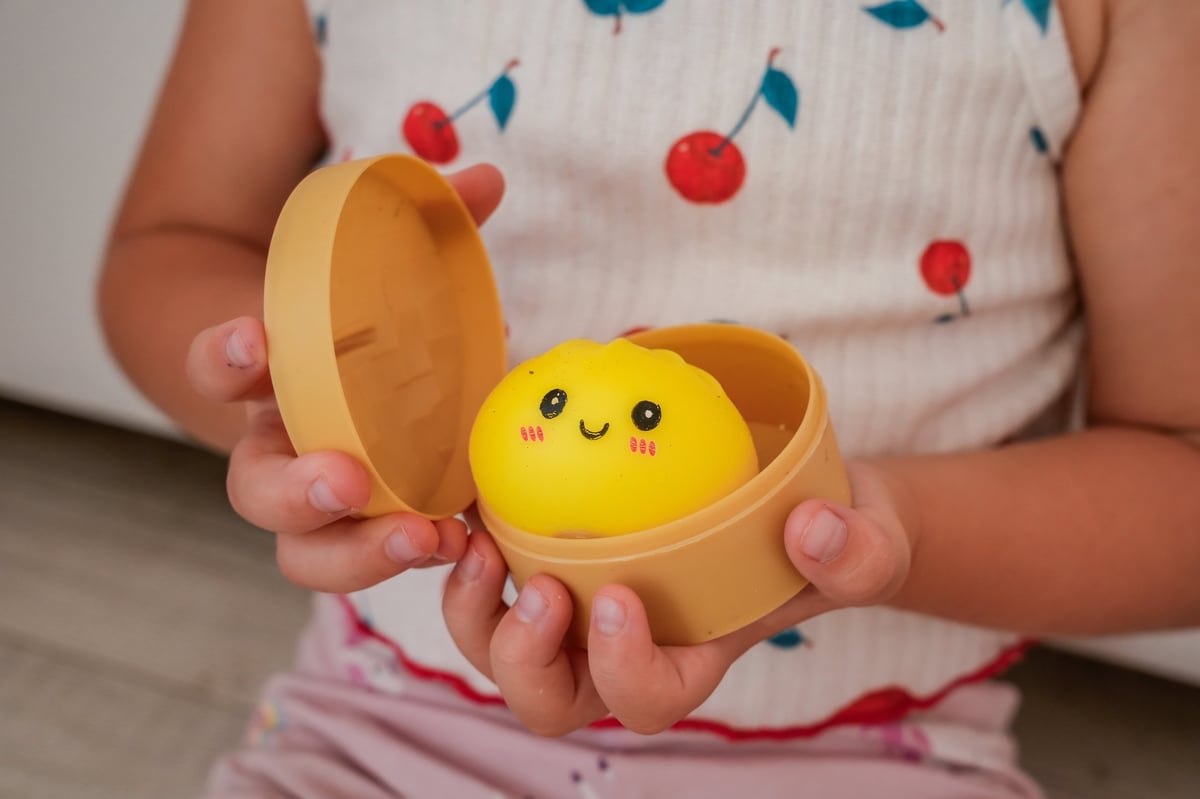 A child holding a steamer basket filled with dumpling squishy toys